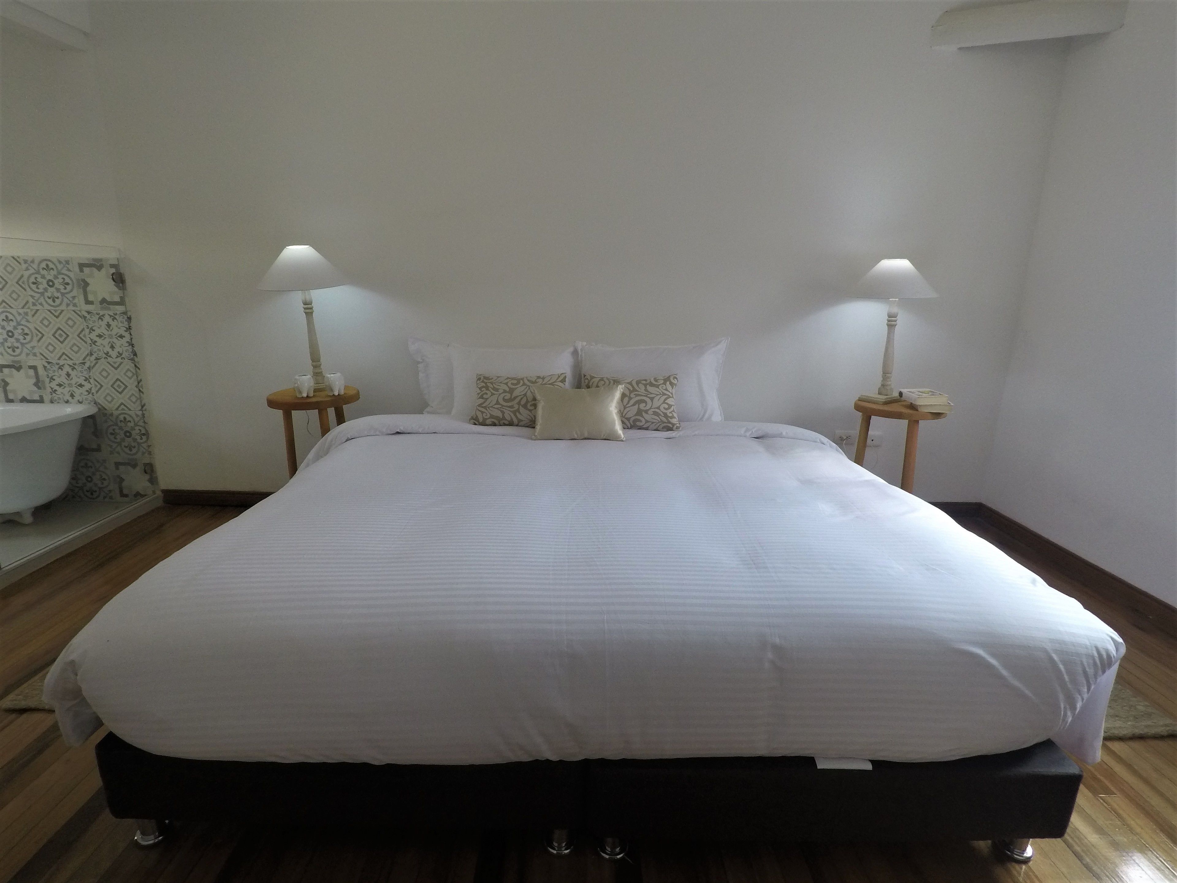 A neatly made bed with white linens, two bedside lamps, and a patterned wall.
