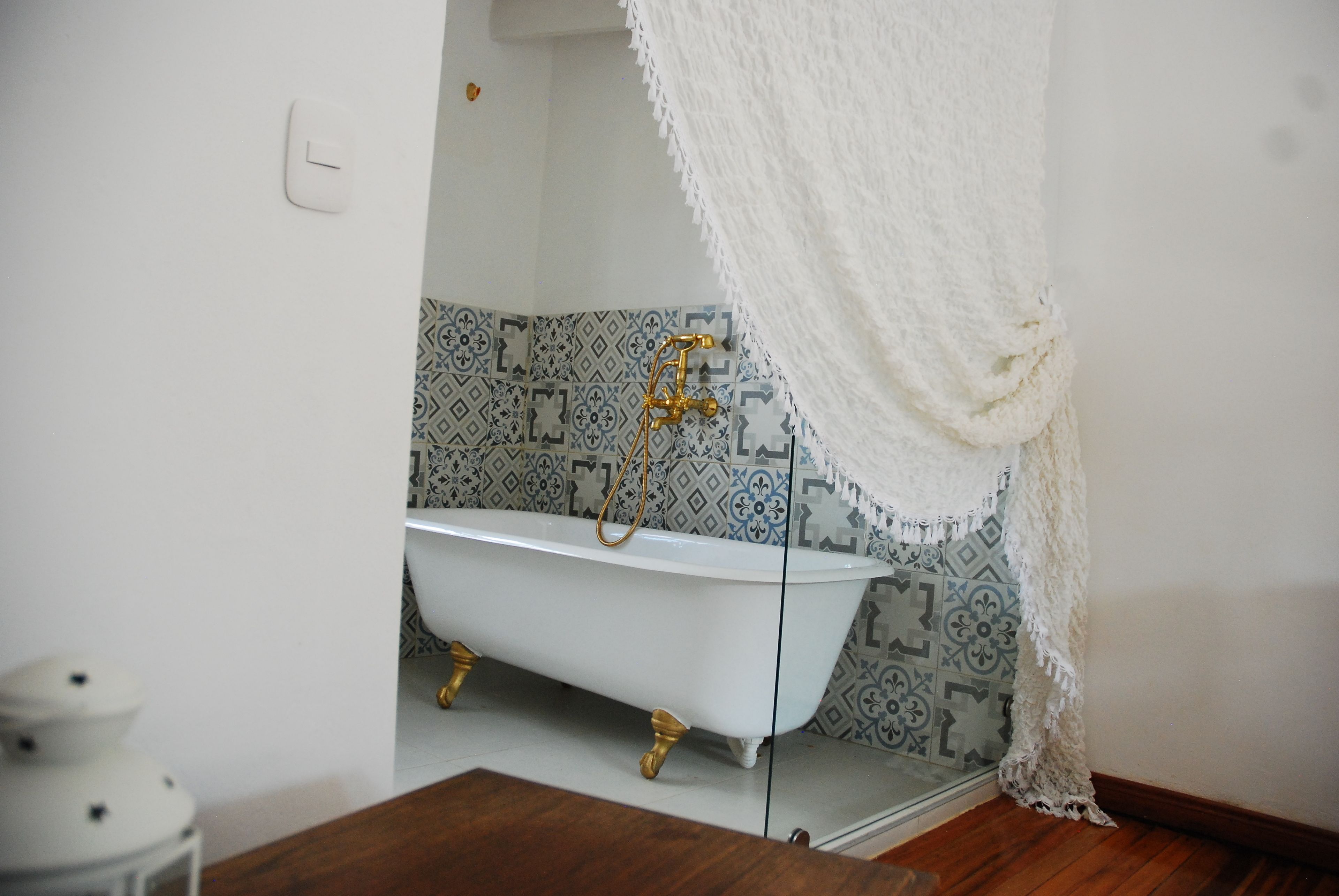 A bathroom with a white bathtub, patterned tiles, and a white shower curtain.