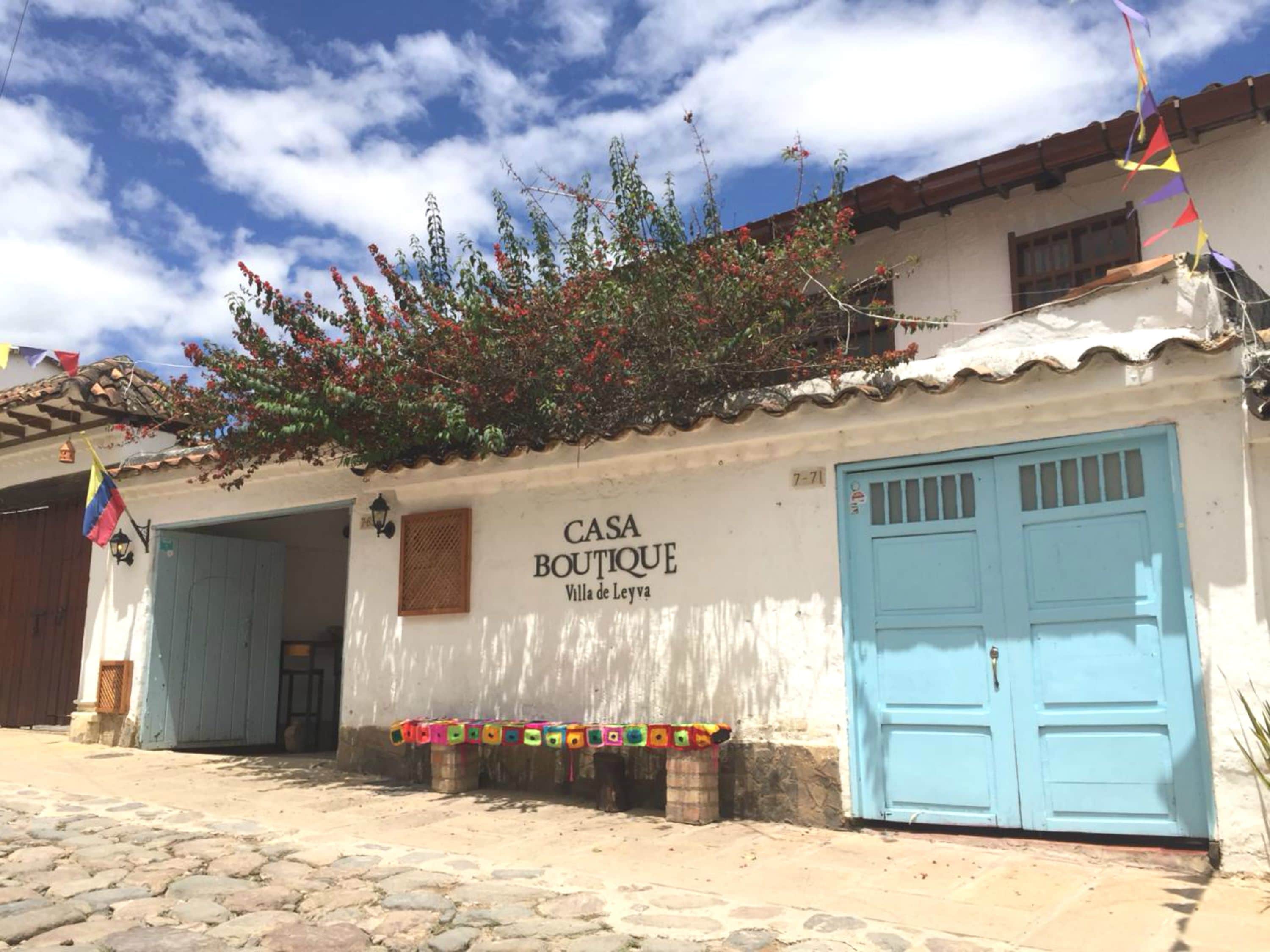 Un bâtiment portant l’inscription « CASA BOUTIQUE Villa de Leyva », avec deux portes bleues et une entrée pavée.