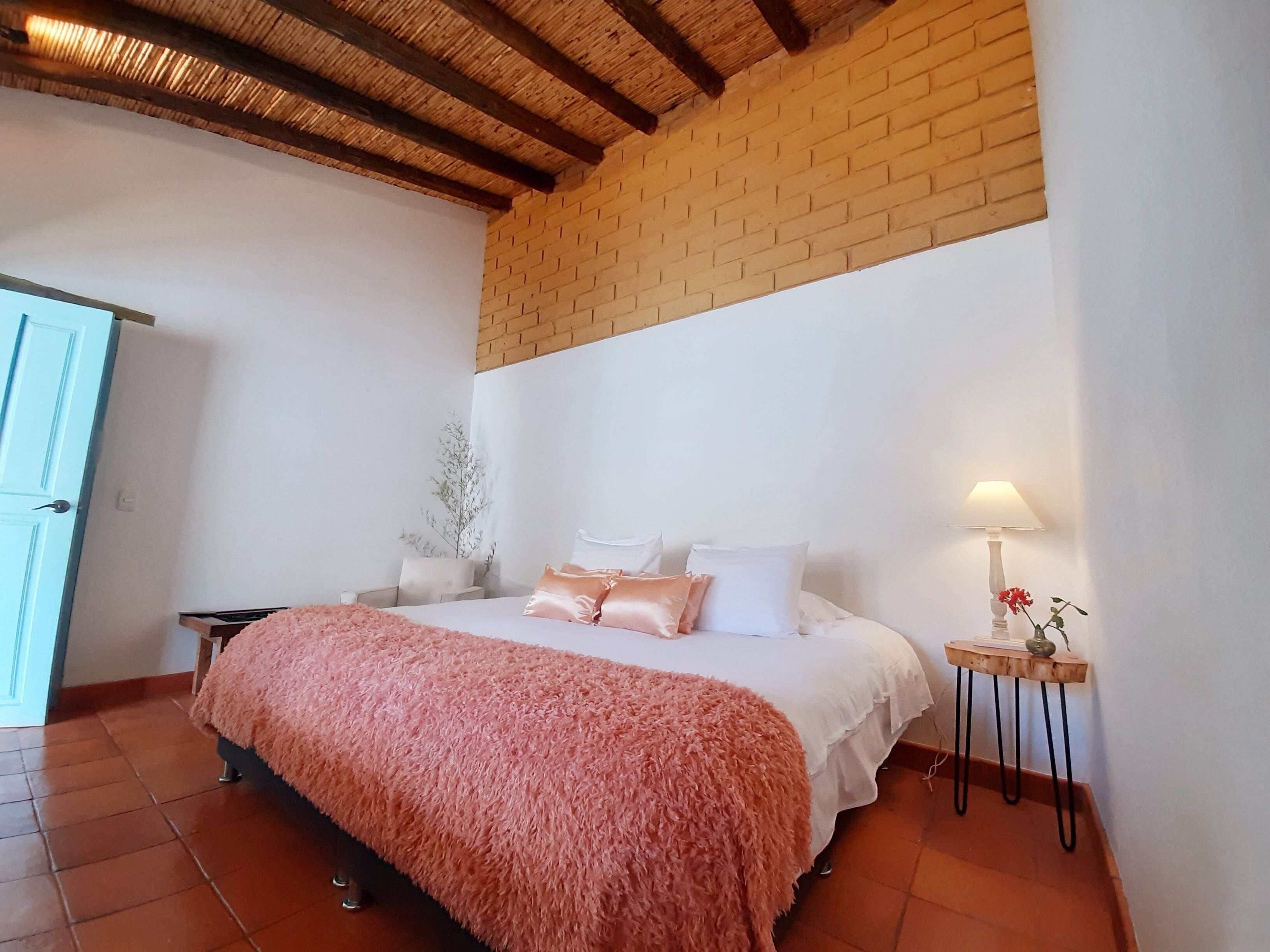 Une chambre à coucher avec un lit, une table de chevet, une lampe et un mur en briques.
