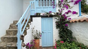 A white building with a blue door and a small balcony. There are potted plants and flowers around the entrance. - Casa Boutique Villa de Leyva - Adults only (Villa de Leyva)