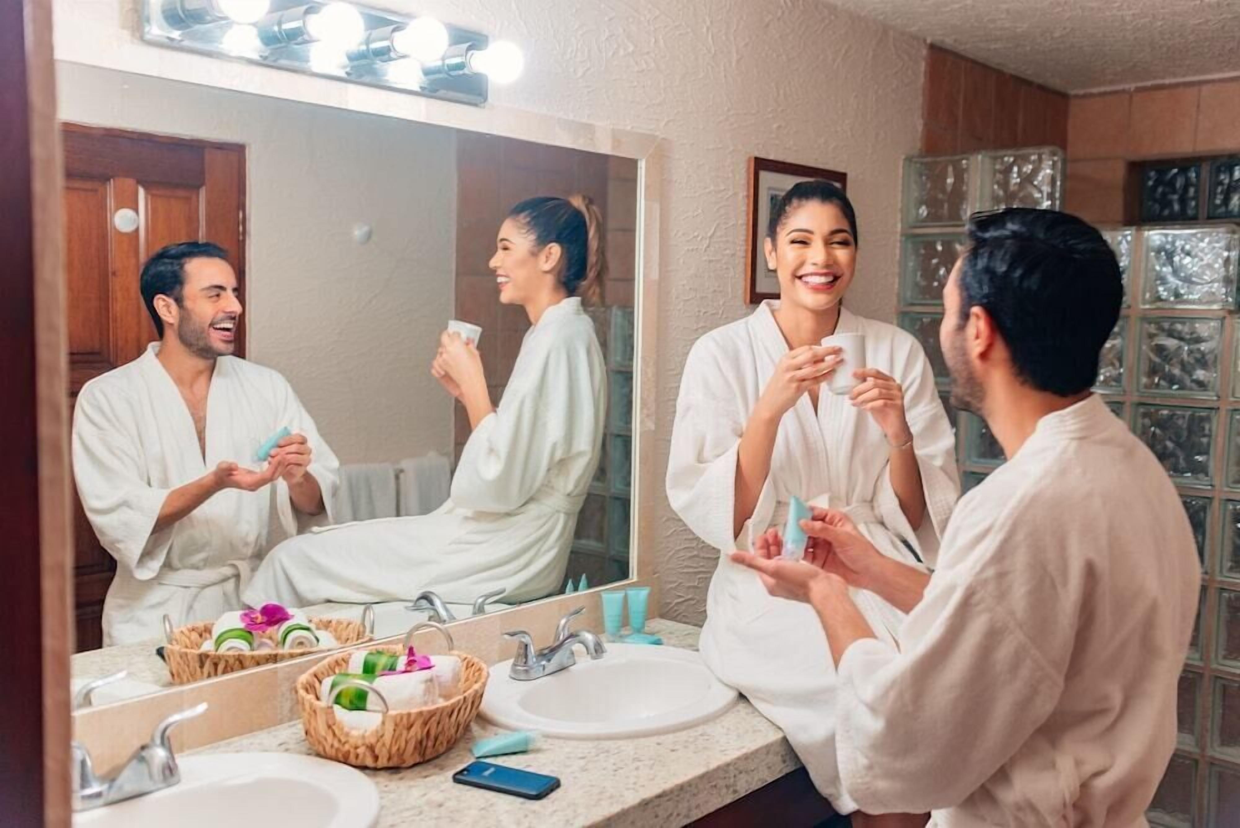 A bathroom with a large mirror, two sinks, and a vanity with toiletries.