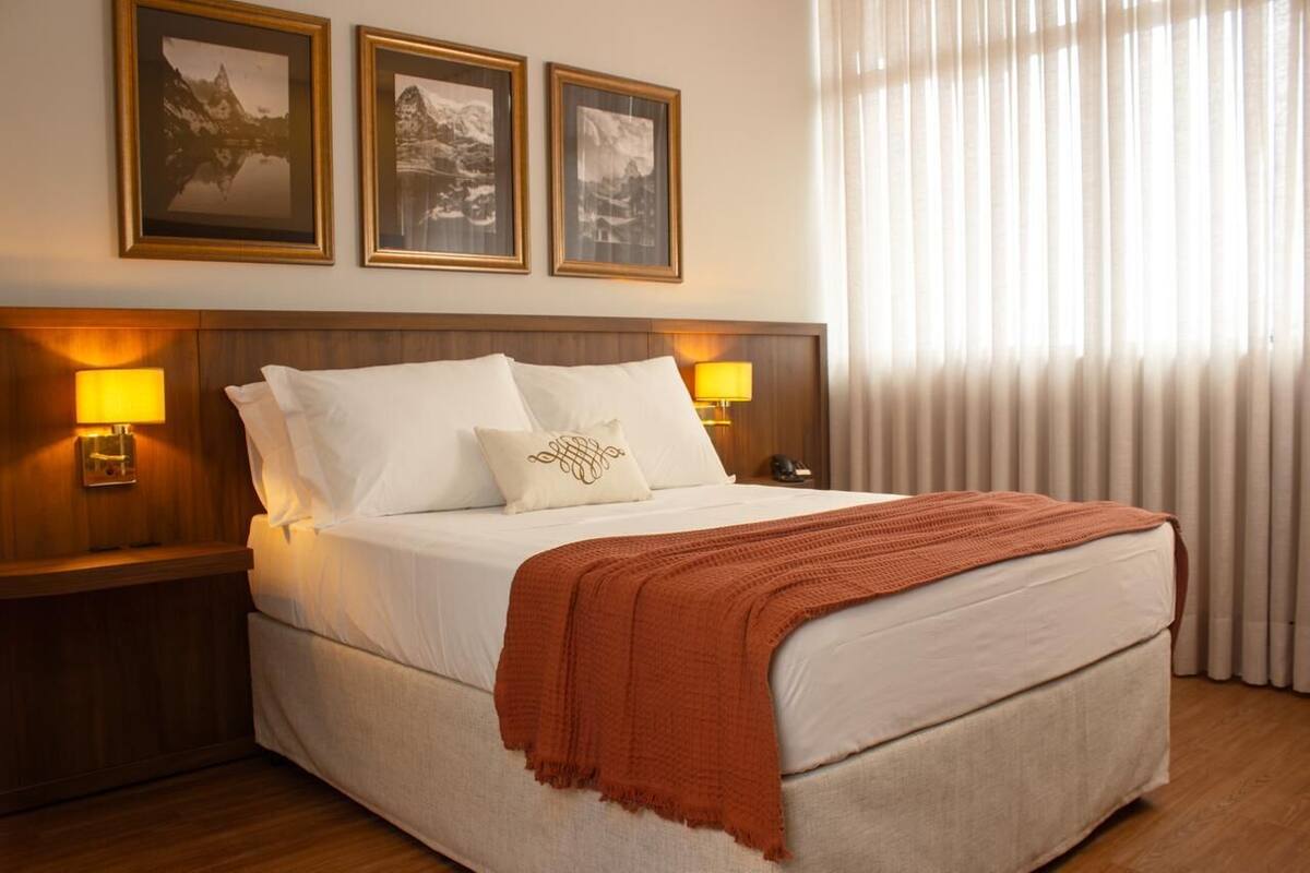 Ein Hotelzimmer mit einem großen Bett, zwei Nachttischlampen und drei gerahmten Bildern an der Wand.
