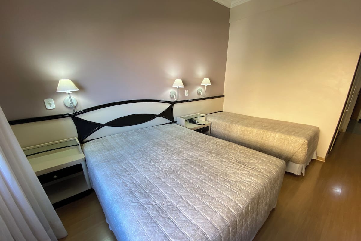 Ein Hotelzimmer mit Bett, Nachttischen, Lampen und einem Spiegel.
