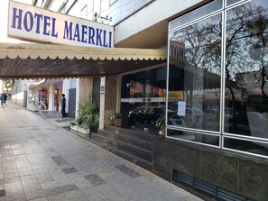 The exterior of Hotel Maerkl with a clear entrance, steps leading up to the door, and a sign indicating a parking area. - Hotel Maerkli (Santo Angelo)