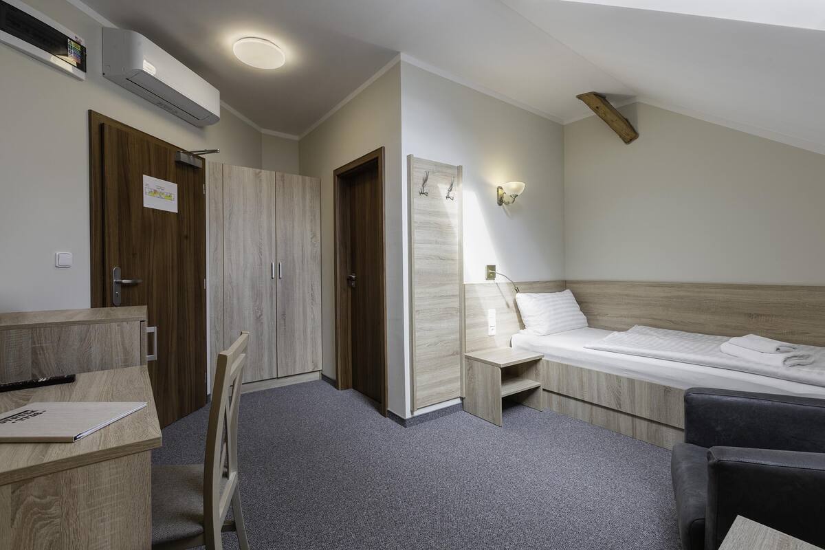 A compact hotel room with a single bed, a desk, and a wardrobe.