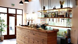 A bar area with a wooden counter, pendant lights, and shelves with bottles. - Statek 1738 (Vsestudy)