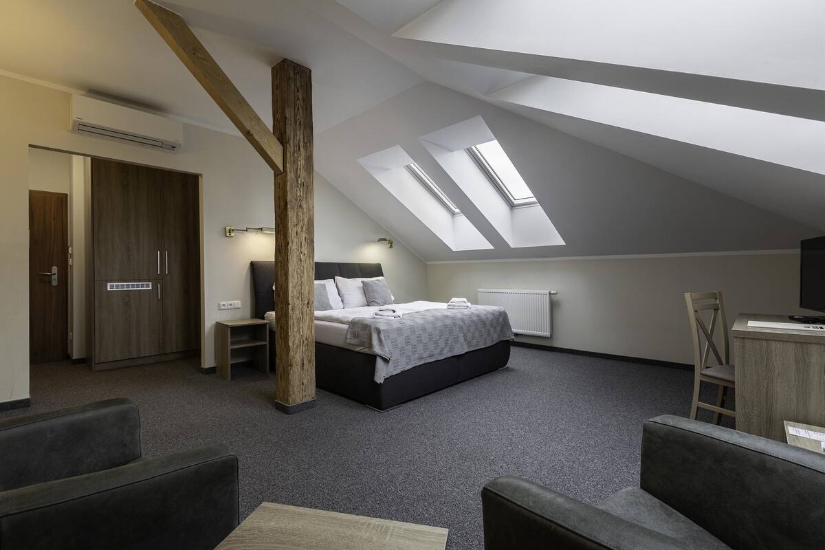 A modern bedroom with a skylight, a bed, a desk, and a chair.
