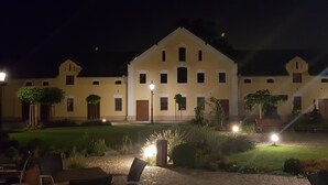 A large building with multiple windows and doors, surrounded by a well-maintained garden with pathways and outdoor seating. - Statek 1738 (Vsestudy)