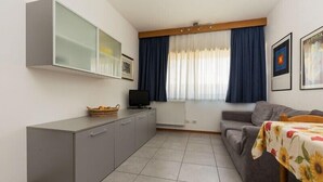 A compact living space with a kitchenette, a sofa, a dining table, and a television. - Residence Capitol (Trento)