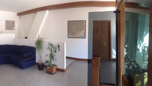 A room with a blue sectional sofa, a potted plant, and a wooden door. - Residence Capitol (Trento)