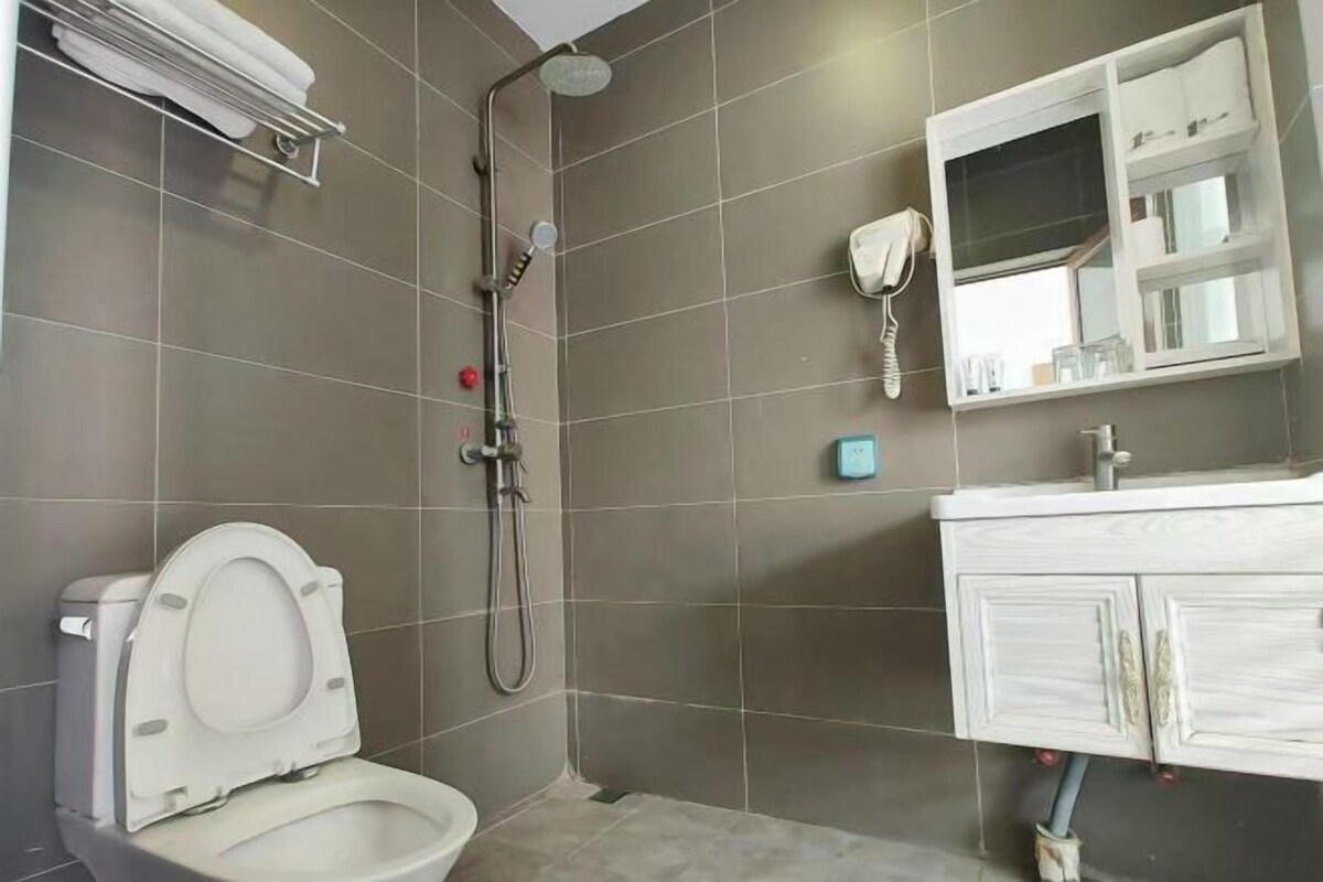 A bathroom with a toilet, a shower, and a vanity with a mirror.