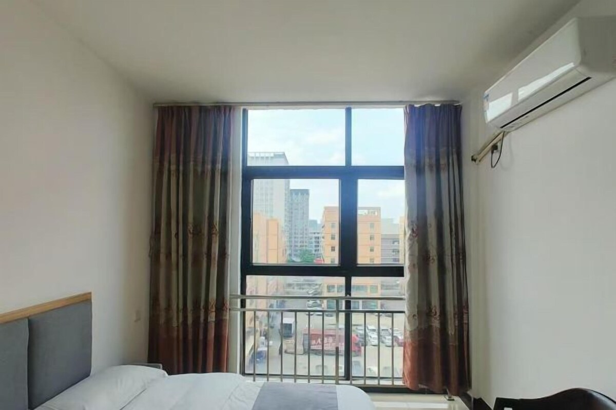Een hotelkamer met een groot raam, een bed, een bureau en een airconditioning.