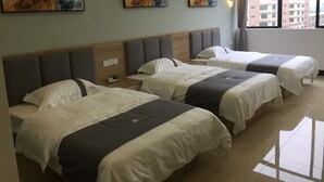 A hotel room with three beds, a wooden headboard, and artwork on the wall. - First Apartment (Jiangmen)