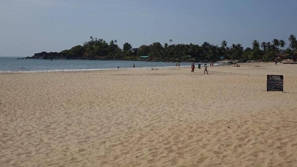 A beach with a sign that reads "Cuba" and a few people walking along the shore. - Eve Resort (Canacona)