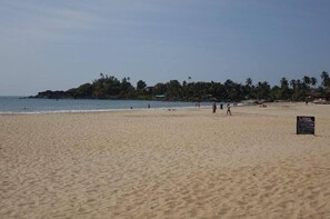 A beach with a sign that reads "Cuba" and a few people walking along the shore. - Eve Resort (Canacona)