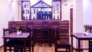 A bar area with wooden furniture and shelves of bottles. - Eve Resort (Canacona)