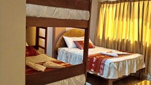 A room with two bunk beds, a wooden desk, and a window with curtains. - Hotel Colquewasi (Cusco)