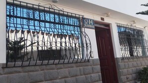 A building with a red door, a blue window, and a metal gate. - Hotel Colquewasi (Cusco)