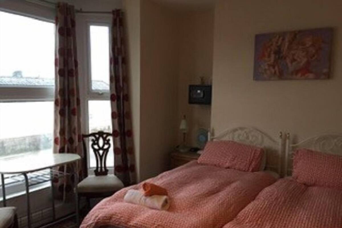 A bedroom with two beds, a table, and a chair.