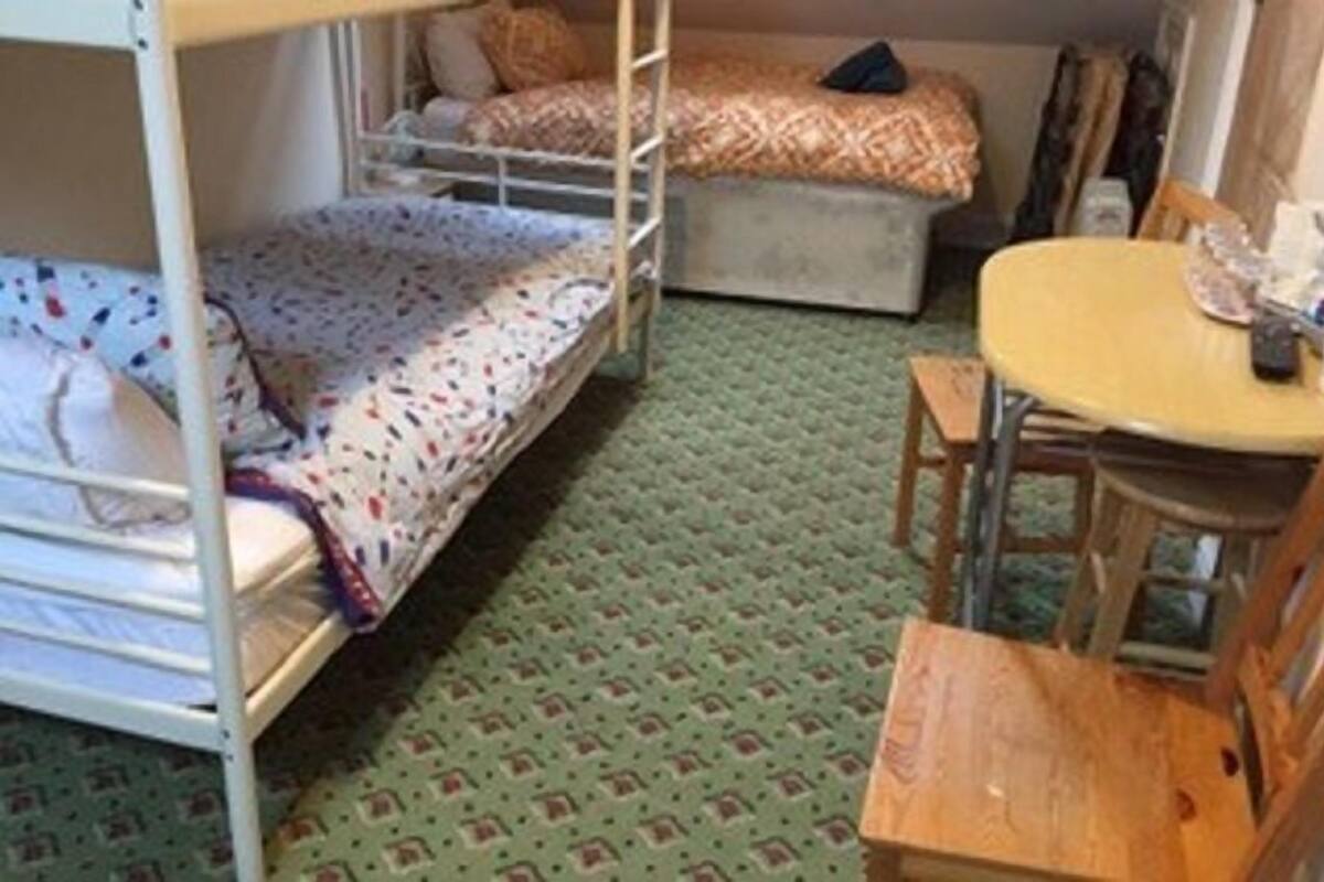 A bunk bed room with a small table and a chair.