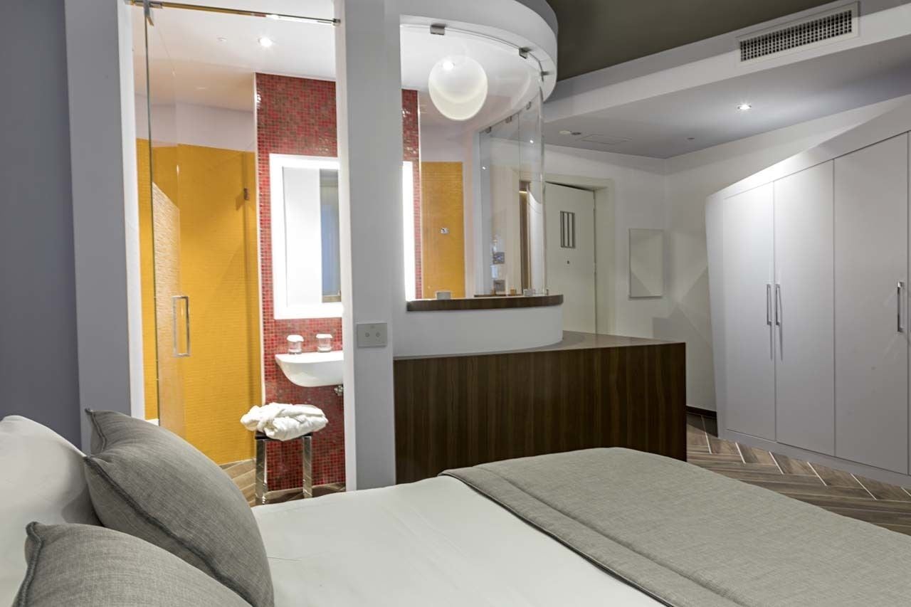Un dormitorio moderno con cama, tocador con espejo y armario.