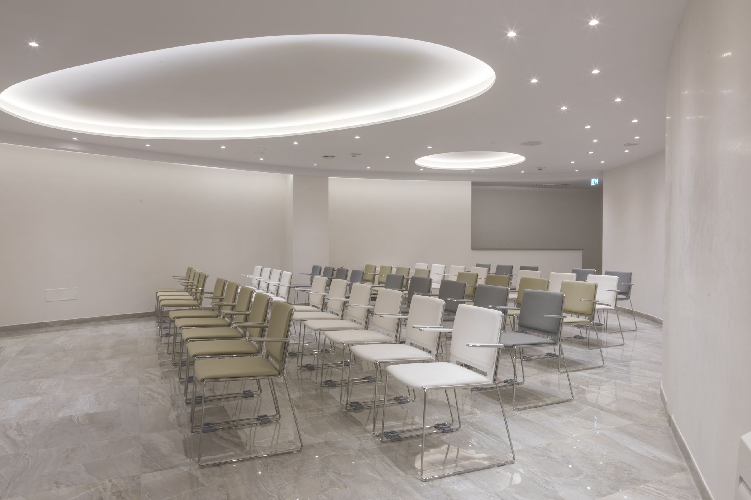 A conference room with rows of chairs and a modern ceiling design.