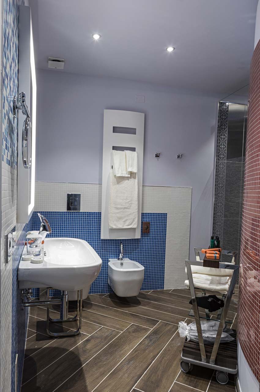 A bathroom with a large sink, a bidet, a mirror, and a shower enclosure.