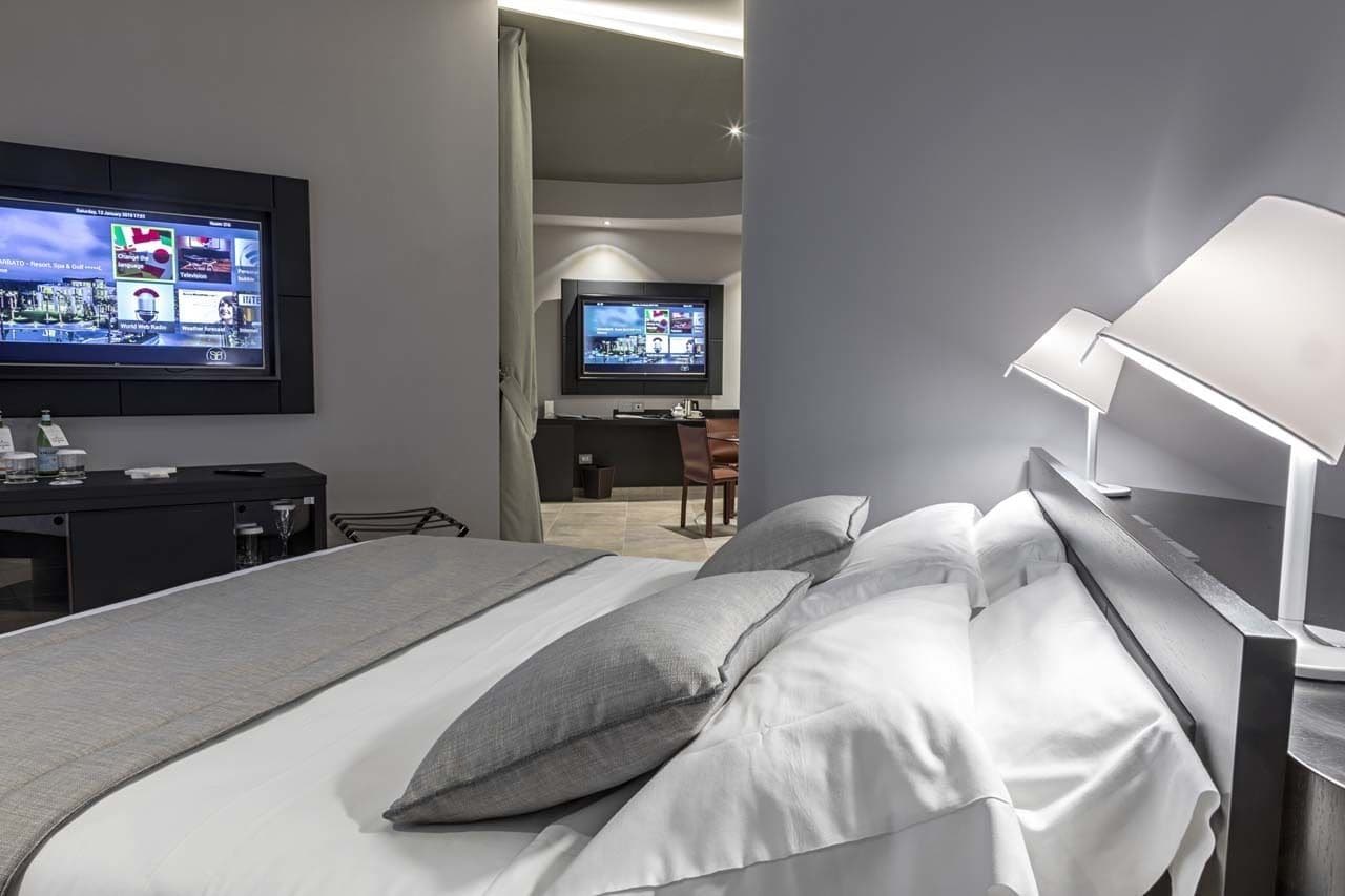 Una habitación de hotel moderna con una cama grande, un escritorio y un televisor montado en la pared.