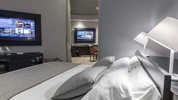 Una habitación de hotel moderna con una cama grande, un escritorio y un televisor montado en la pared.