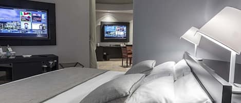 Una habitación de hotel moderna con una cama grande, un escritorio y un televisor montado en la pared.