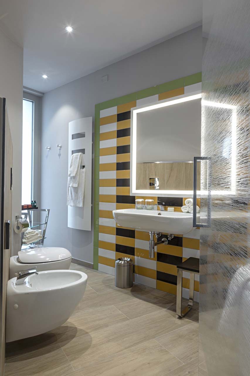 Un baño moderno con un lavamanos blanco, un espejo y un inodoro.