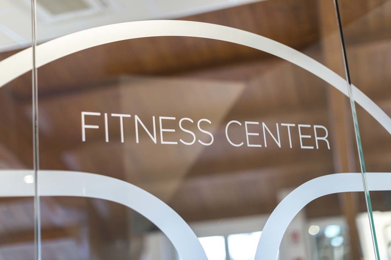 Skilt med ordene "FITNESS CENTER" på en glasdør.