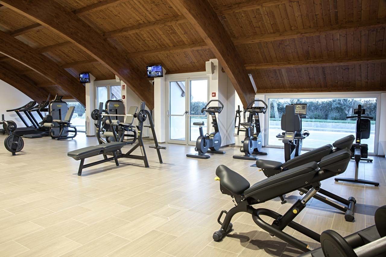 Un gimnasio con varios equipos de ejercicio, entre ellos, cintas de correr, elípticas y máquinas de pesas.