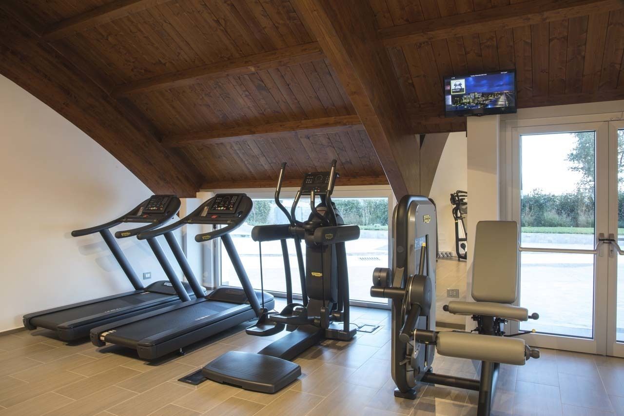 Et fitnessrum med løbebånd, crosstrainere og en vægtbænk.
