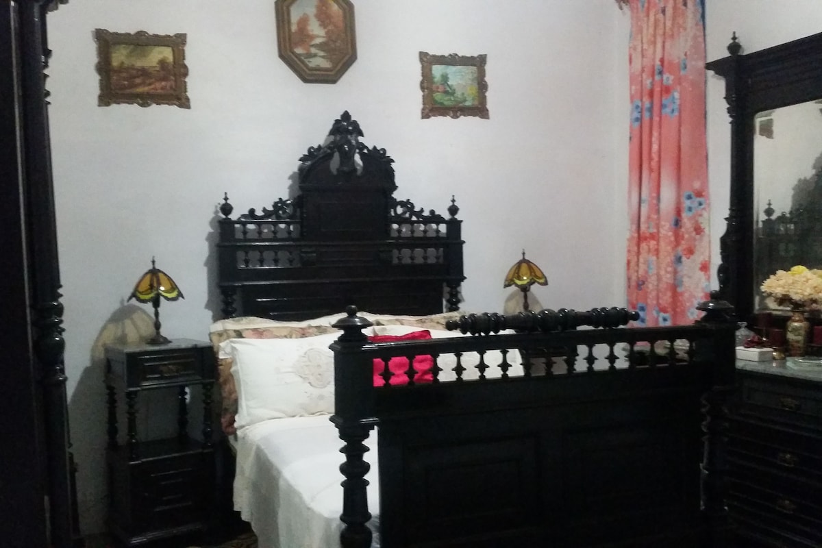 Une chambre à coucher avec un lit en bois, deux lampes de chevet, un miroir et une commode.