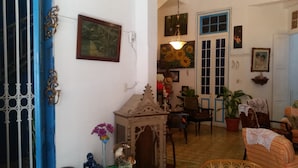 Un salon chaleureux avec une porte bleue, un meuble en bois, une chaise, une table et une plante en pot.