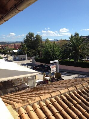 A rooftop terrace with terracotta tiles, a sign for 'CAVERNAS de Atitlán', and a view of a parking area with a car and palm trees.