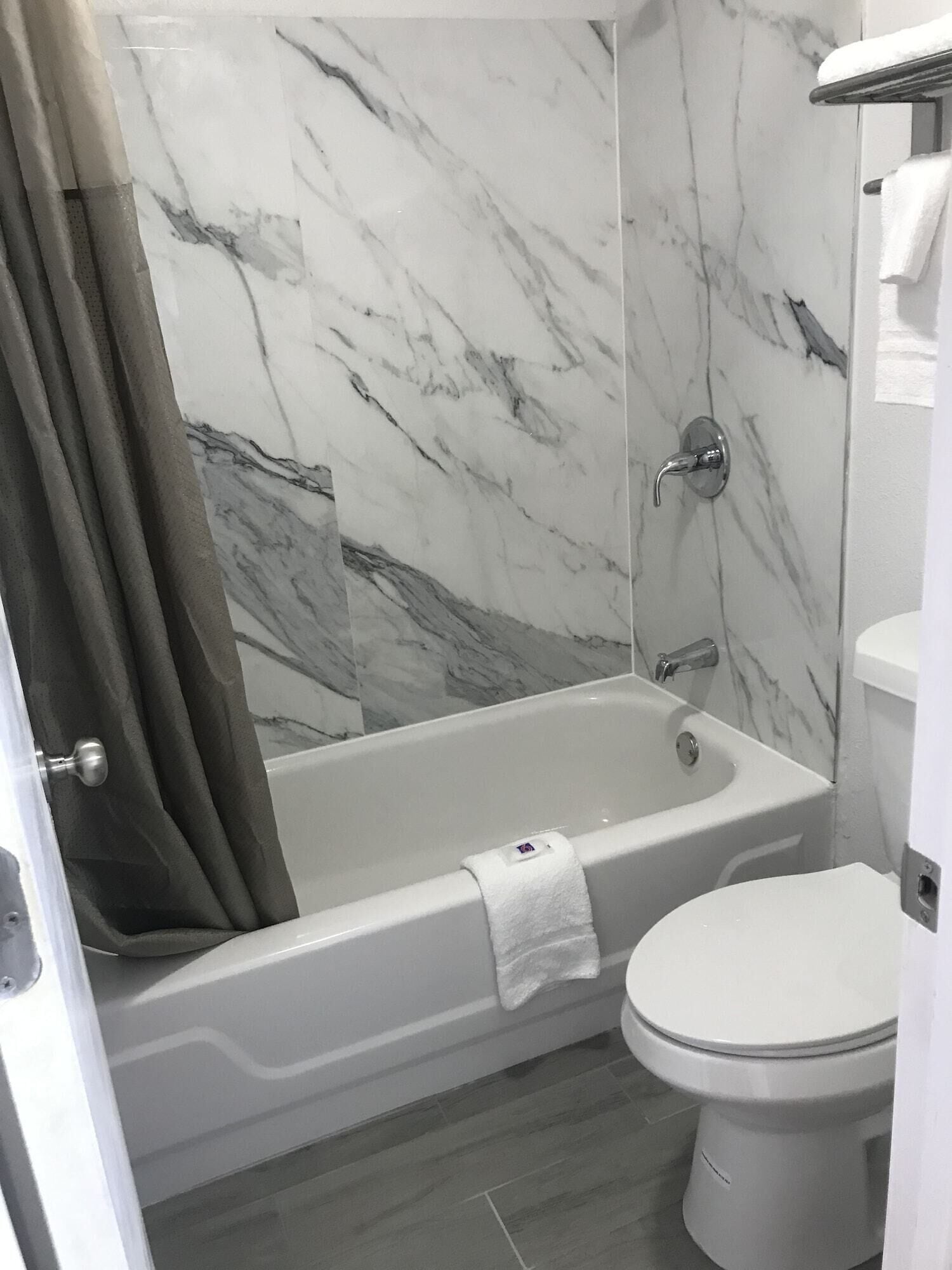 A bathroom with a bathtub, toilet, and marble walls.