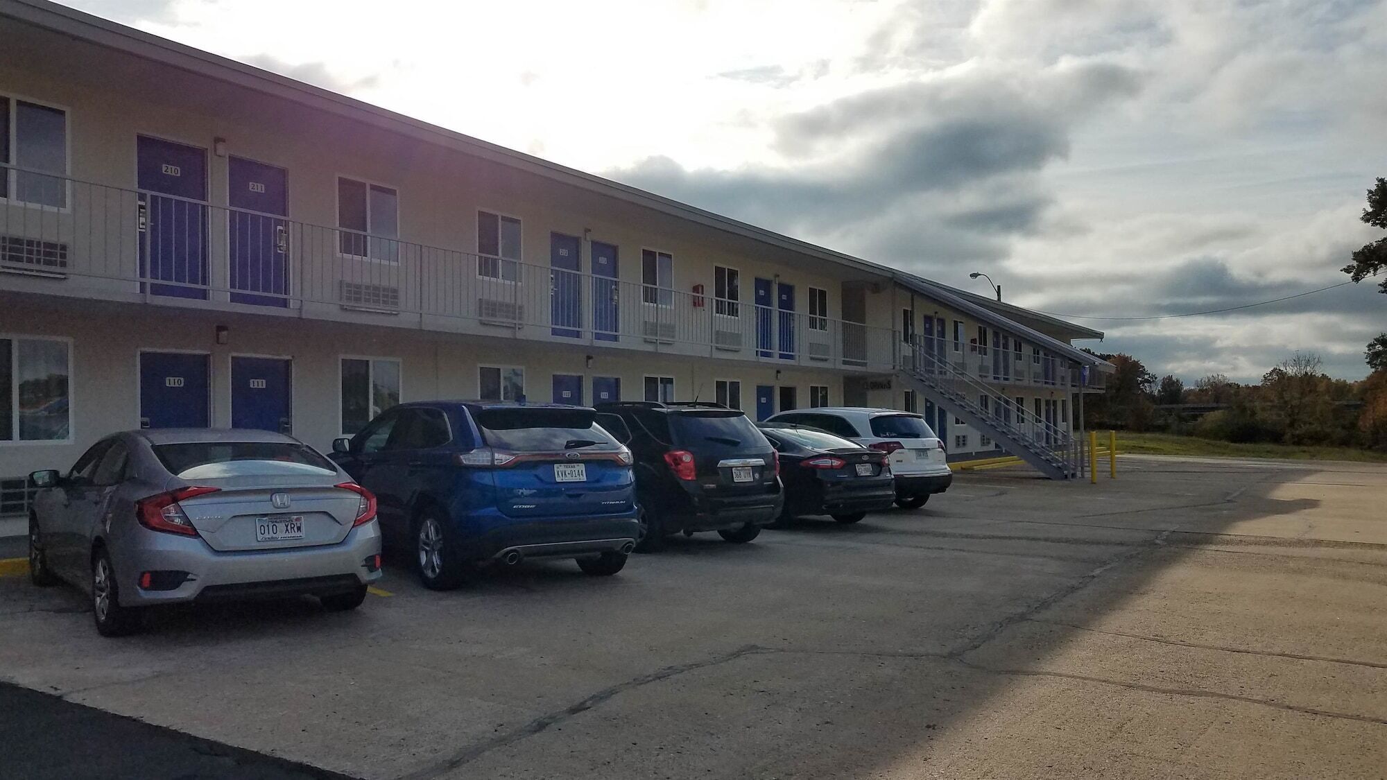 A motel with multiple parking spaces and a building with numbered doors.