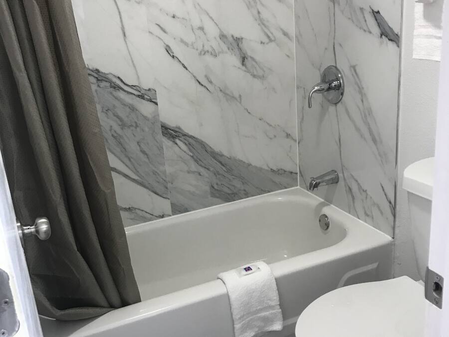 A bathroom with a bathtub, toilet, and marble walls.