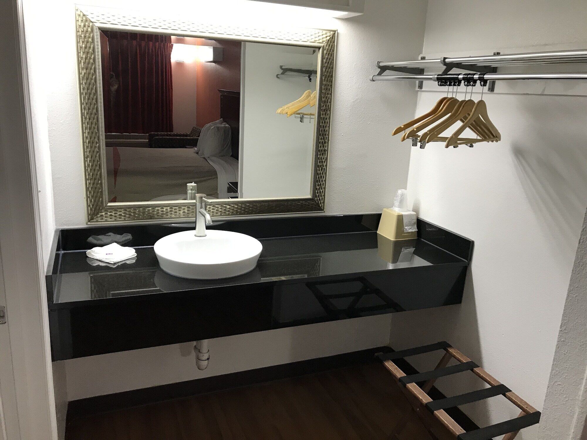 A modern bathroom with a round white sink, a large mirror, and a towel rack.