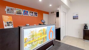A hotel reception area with a modern design, featuring a reception desk with a digital display and a sign promoting the hotel.