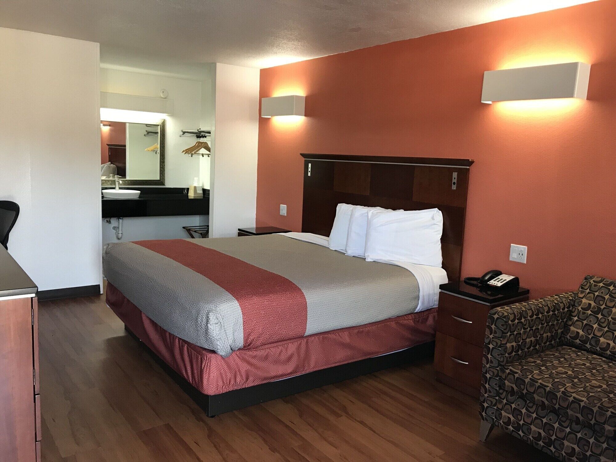 A hotel room with a bed, bedside table, and a chair.