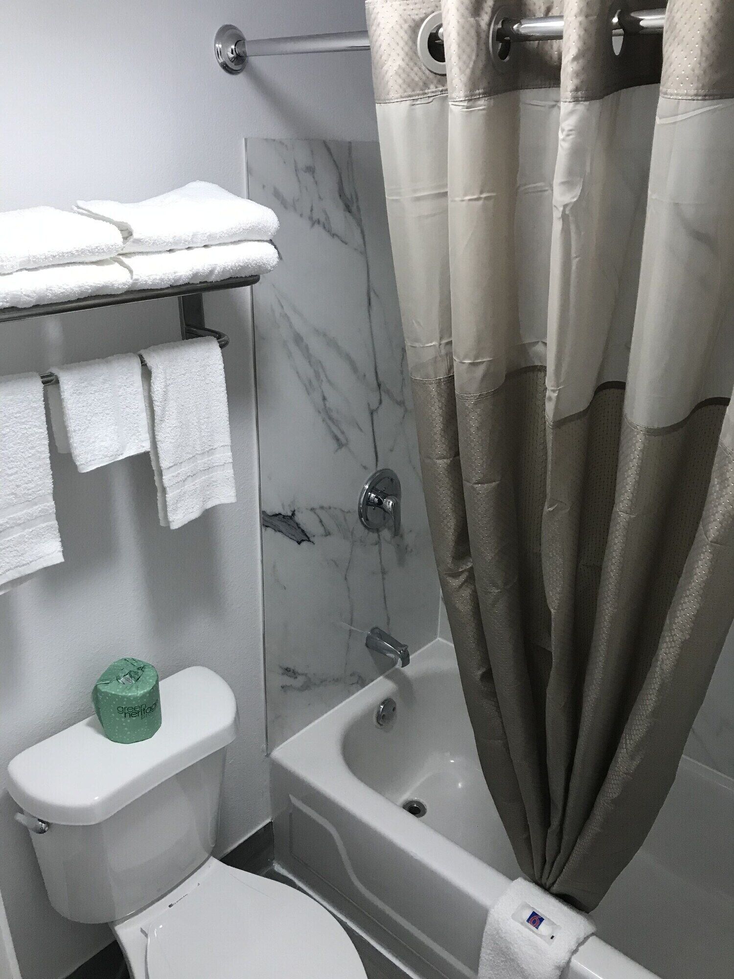 Un baño con inodoro, bañera y cortina de ducha.