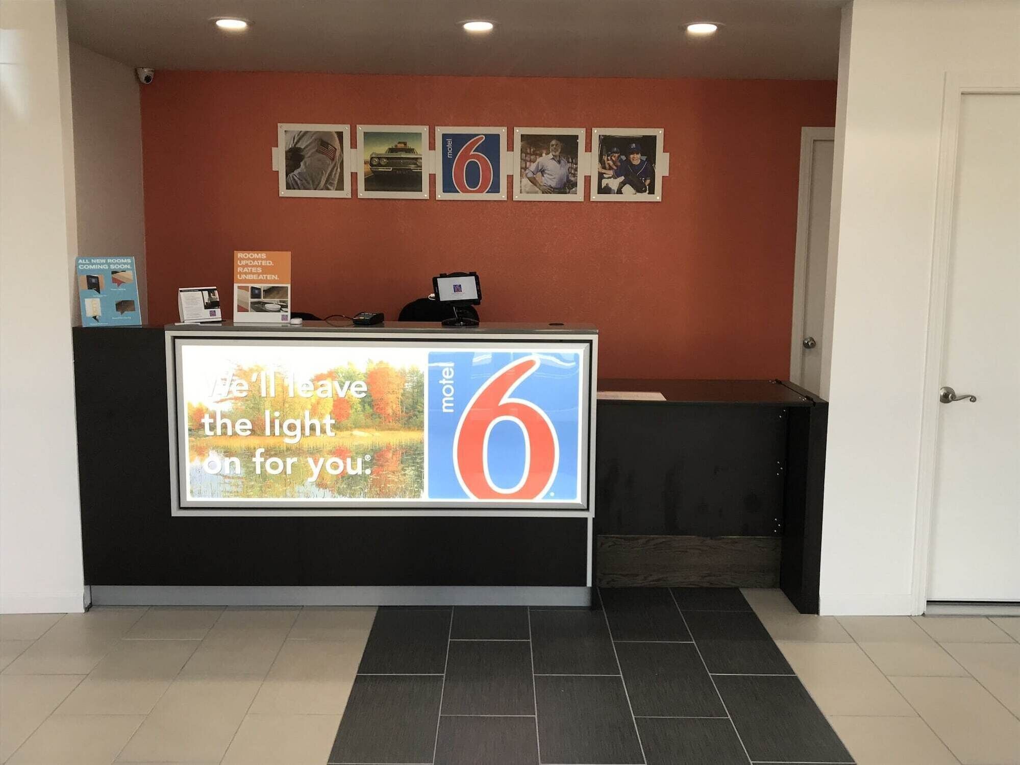A hotel reception desk with a large illuminated sign reading "I'll leave the light on for you."