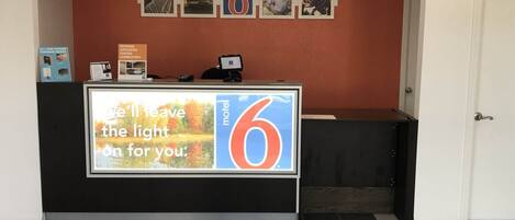 A hotel reception desk with a large illuminated sign reading "I'll leave the light on for you."
