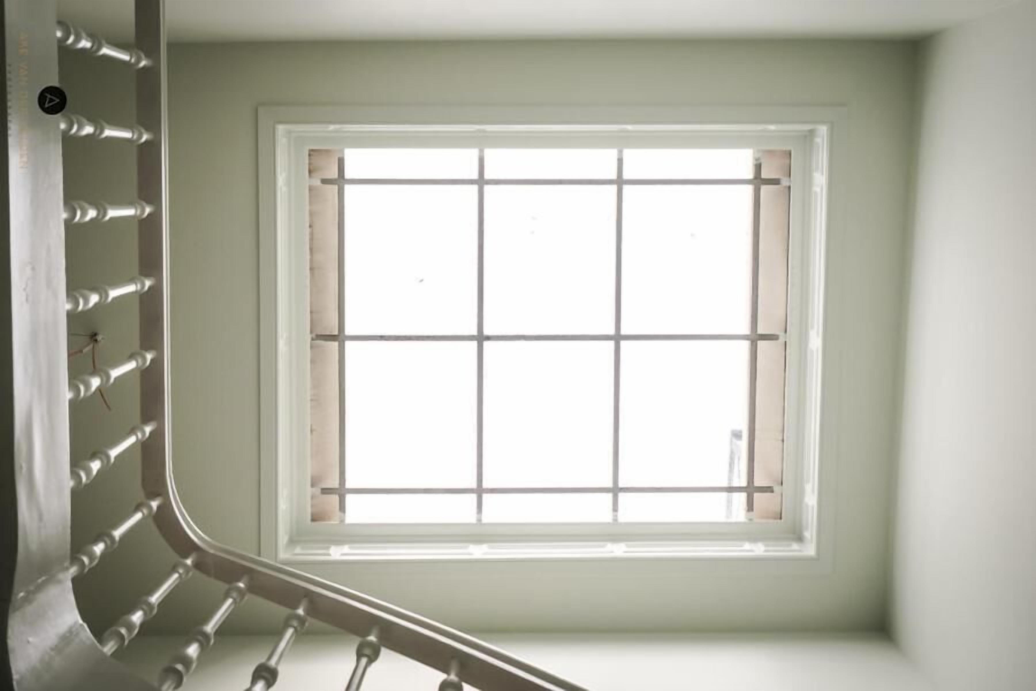 A room with a window, a metal railing, and a door.