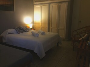 A hotel room with a bed, two bedside tables, a chair, and a wardrobe. - Hostal plaza (Cienfuegos)