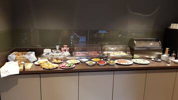 A buffet counter with various food items and a coffee machine.